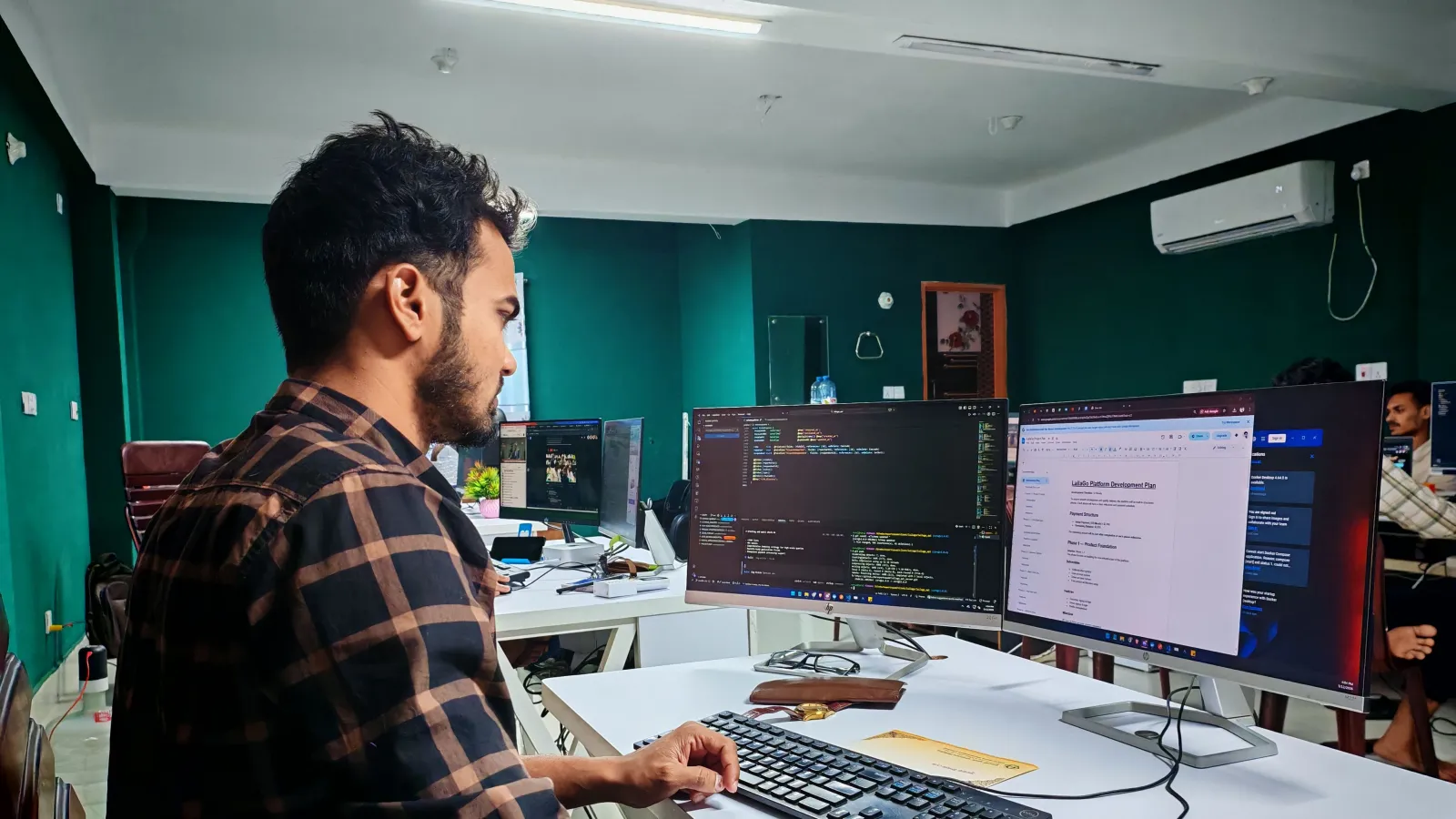 Photo: Zayed Hossain on Pexels A developer at two screens, one with code and one with a project plan